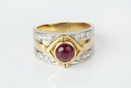 A RUBY AND DIAMOND DRESS RING, the tapered band centred with a circular cabochon ruby in lozenge-