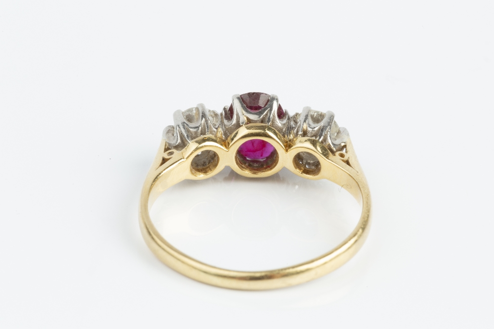 A RUBY AND DIAMOND THREE STONE RING, the oval mixed-cut ruby claw set between two round brilliant- - Image 2 of 3