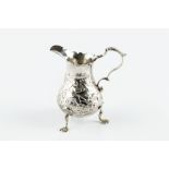 A GEORGE II SILVER BALUSTER CREAM JUG, embossed and engraved with a seated figure holding a bird,