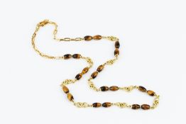 A TIGER'S EYE BEAD NECKLACE, designed as a line of reeded hoop-shaped links, spaced by pairs of