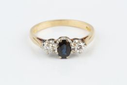 A SAPPHIRE AND DIAMOND THREE STONE RING, the oval mixed-cut sapphire claw set between two round