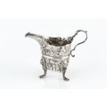 AN 18TH CENTURY IRISH SILVER CREAM JUG, the girdled body embossed and engraved with flowers and