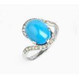 A DIAMOND SET DRESS RING, of crossover design, the oval turquoise coloured cabochon claw set between
