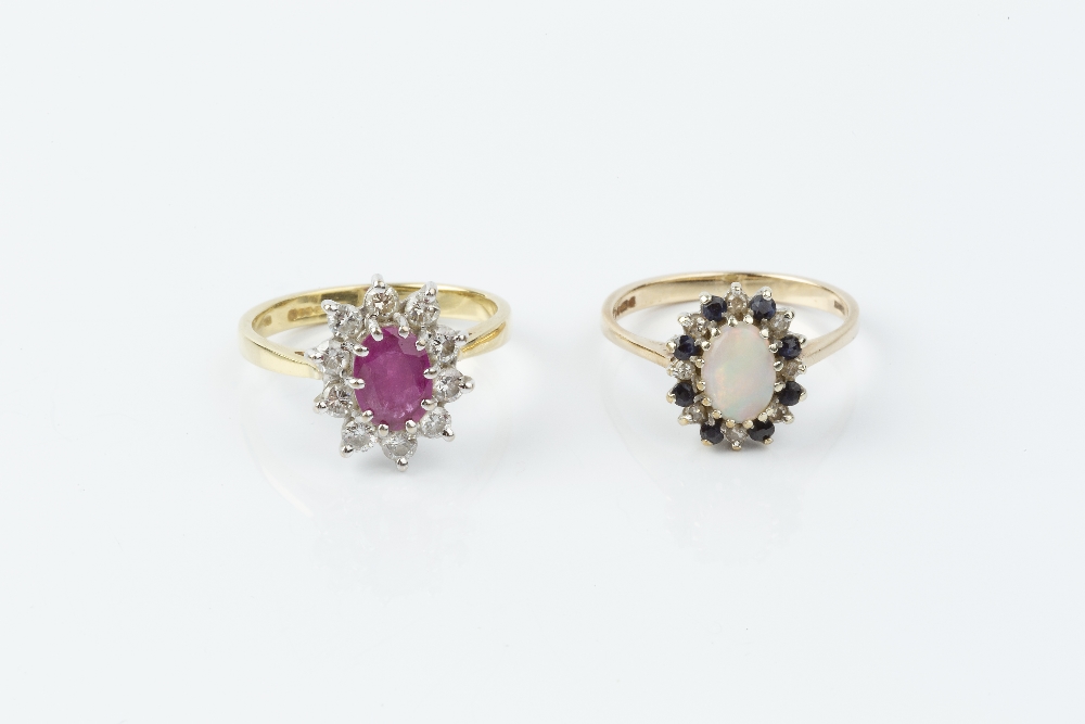 A RUBY AND DIAMOND CLUSTER RING, the oval mixed-cut ruby claw set within a round brilliant-cut
