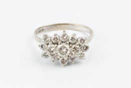 A DIAMOND CLUSTER RING, centred with a trio of round brilliant-cut diamonds, bordered by graduated