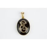 A VICTORIAN DIAMOND AND ONYX LOCKET PENDANT, the oval hinged locket with onyx cover, applied with