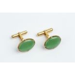 A PAIR OF JADE CUFFLINKS, each oval jadeite cabochon claw set within a reeded surround, on hinged