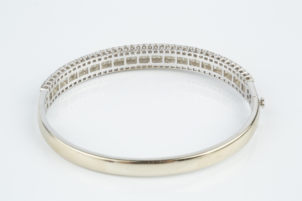 A DIAMOND BANGLE, of hinged oval form, channel set to the front with a line of baguette-cut - Image 3 of 5