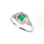 AN EMERALD AND DIAMOND PANEL RING, the octagonal step-cut emerald millegrain collet set within a