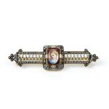 A 19TH CENTURY ENAMEL AND GEM SET BAR BROOCH, the cushion-shaped garnet painted with a portrait