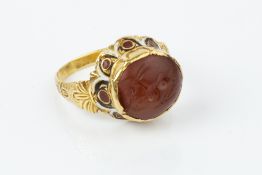 AN ENAMEL AND HARDSTONE INTAGLIO RING, the 19th century fluted setting decorated with scalloped red,
