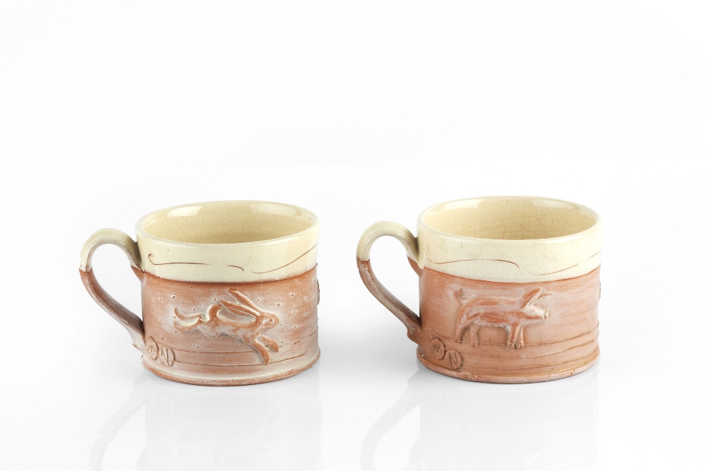 Philip Wood (b.1957) A pair of mugs moulded with animals, the rims with band of cream glaze