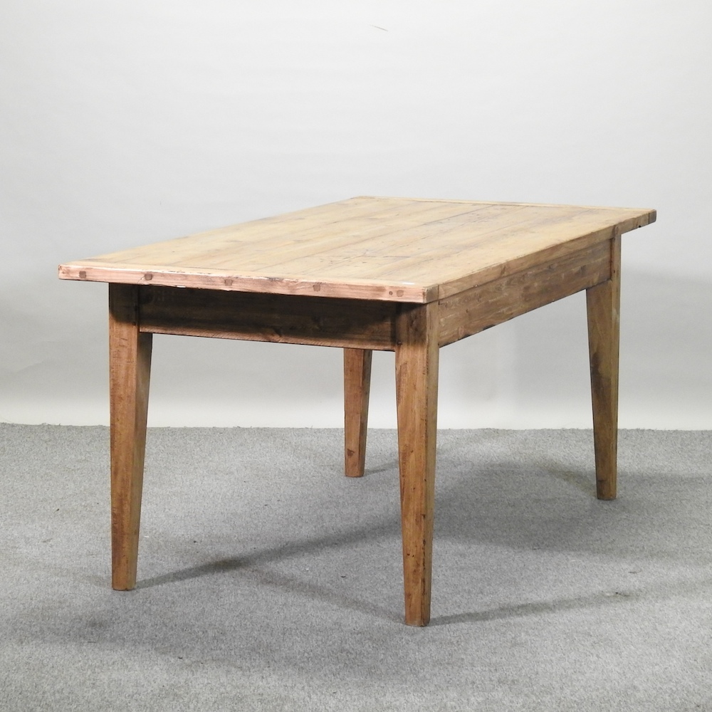 A rustic pine dining table, with a plank top, on square tapered legs,