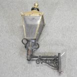 A brass lantern, mounted on a wrought iron bracket,