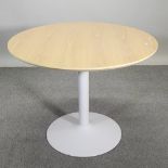 A modern light oak circular dining table, on a painted metal base,