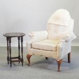 A 1930's Queen Anne style cream upholstered armchair, together with a carved oak occasional table,