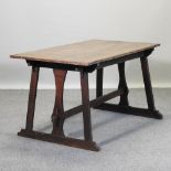 An Arts and Crafts oak centre table, with trestle ends, united by a stretcher,