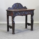 A 19th century carved oak green man side table, with a gallery back,