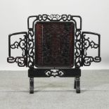 A Chinese carved rosewood fire screen, with an adjustable panel,