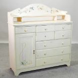 A cream painted sideboard, with floral decoration, and a gallery back,