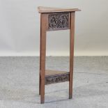 An Arts and Crafts triangular carved oak occasional table,