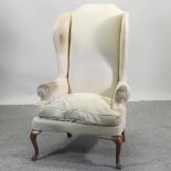 A 19th century style cream upholstered wing armchair,