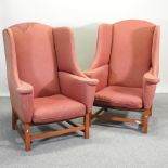 A pair of large red upholstered wing armchairs