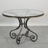A wrought iron dining table, with a circular glass top,