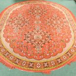 A large oval woollen carpet, on a red ground,