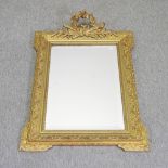 An early 20th century French gilt gesso framed wall mirror, with a scrolled cresting,