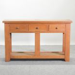 A modern light oak two tier side table, containing three short drawers,