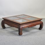 An oriental hardwood coffee table, with a glass top,