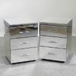 A pair of mirrored glass bedside cabinets,