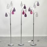 A set of three contemporary chrome standard lamps, with coloured glass shades,