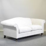 A cream upholstered hump back sofa, on turned legs and castors,