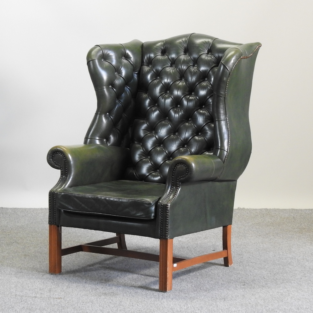 A green upholstered button back wing armchair,