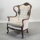 A carved and tan upholstered button back armchair, of large proportions,