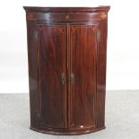 A George III mahogany and inlaid bow front hanging corner cabinet,