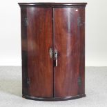 A George III mahogany bow front corner cabinet,