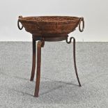 A rusted metal circular fire pit, on legs,