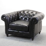 A large dark brown leather upholstered button back armchair,