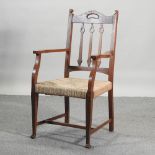 An Arts and Crafts rush seated oak open armchair,