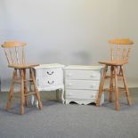 A pair of beech spindle back bar stools, together with a small white painted chest of drawers,