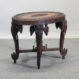 An Indian carved hardwood occasional table, on elephant supports,