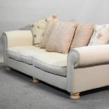 A modern cream upholstered sofa, with loose cushions,