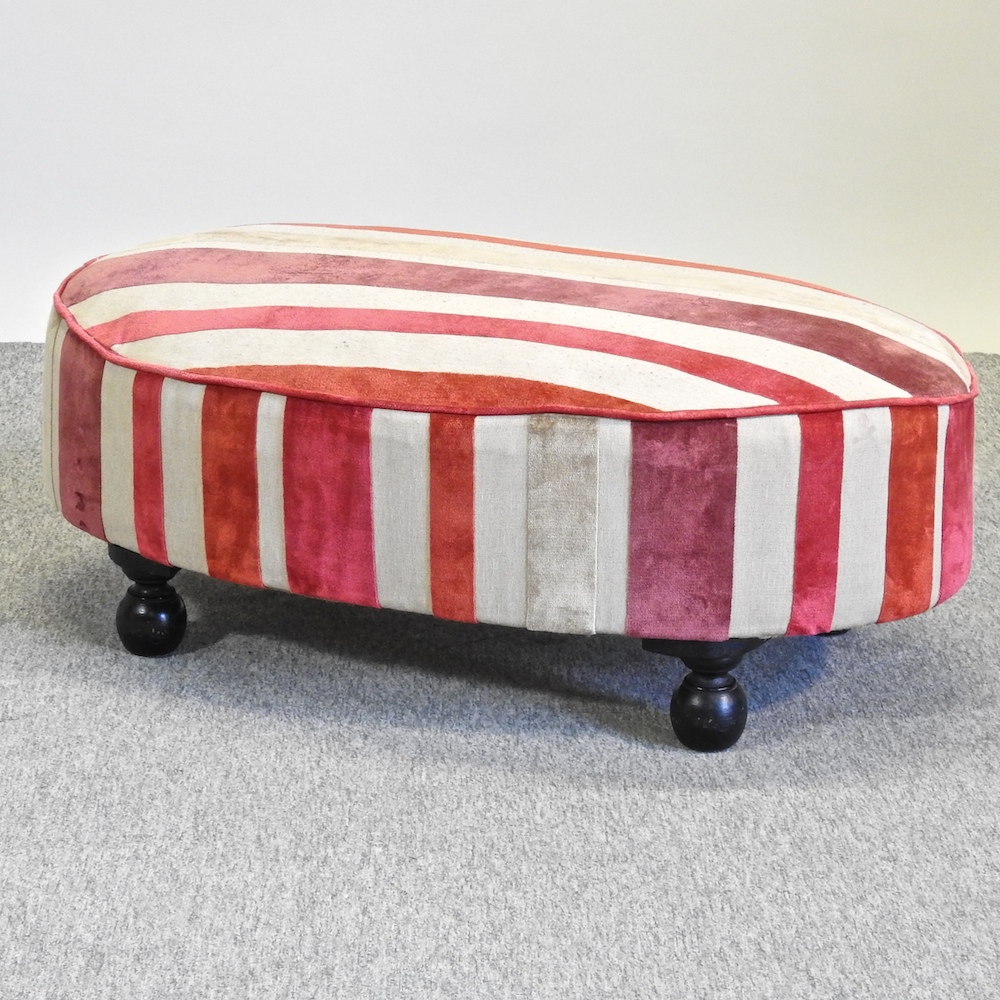 A modern oval shaped footstool, with striped upholstery,