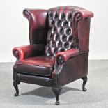 A Thomas Lloyd red leather upholstered button back wing armchair,