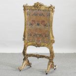 A Victorian embroidered fire screen, with a gilt gesso frame,