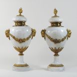 A pair of white marble urns, with gilt ram's head decoration,