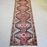 A Heriz style woollen runner, on a red ground, 310 x 110cm,